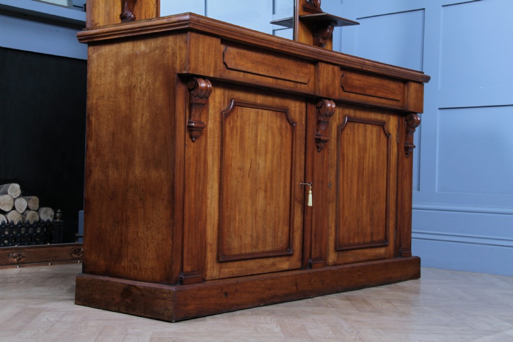 A Victorian mahogany mirror-back sideboard featuring two panelled cabinet doors, upper drawers, tiered side shelves, and a decorative carved cresting. View XX