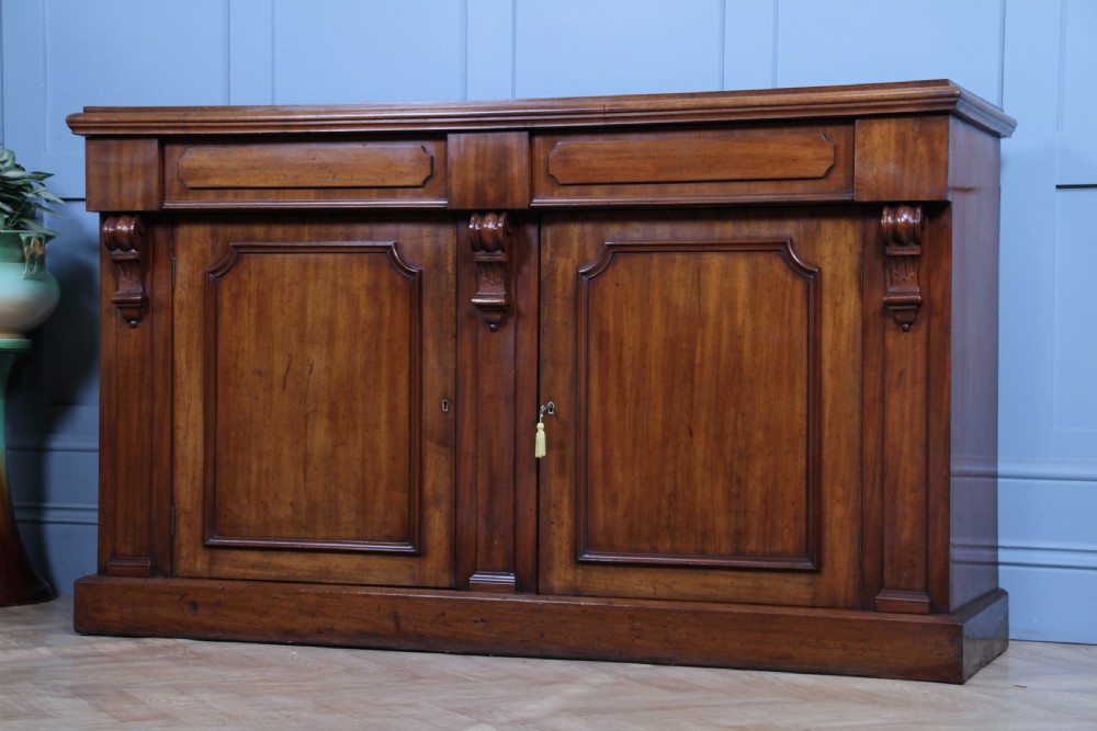 A Victorian mahogany mirror-back sideboard featuring two panelled cabinet doors, upper drawers, tiered side shelves, and a decorative carved cresting. View XXI