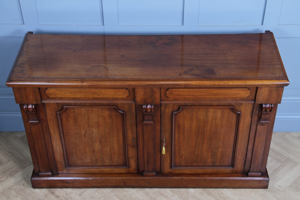 A Victorian mahogany mirror-back sideboard featuring two panelled cabinet doors, upper drawers, tiered side shelves, and a decorative carved cresting. View XXII