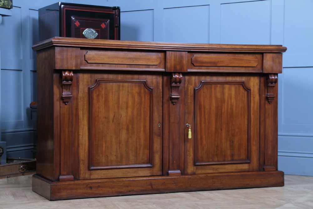 A Victorian mahogany mirror-back sideboard featuring two panelled cabinet doors, upper drawers, tiered side shelves, and a decorative carved cresting. View XXIII