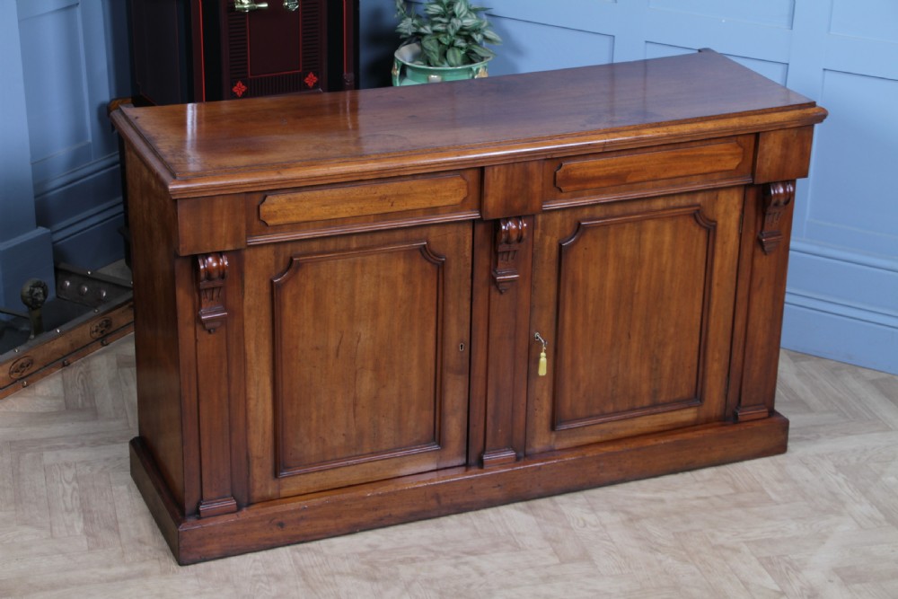 A Victorian mahogany mirror-back sideboard featuring two panelled cabinet doors, upper drawers, tiered side shelves, and a decorative carved cresting. View XXIV