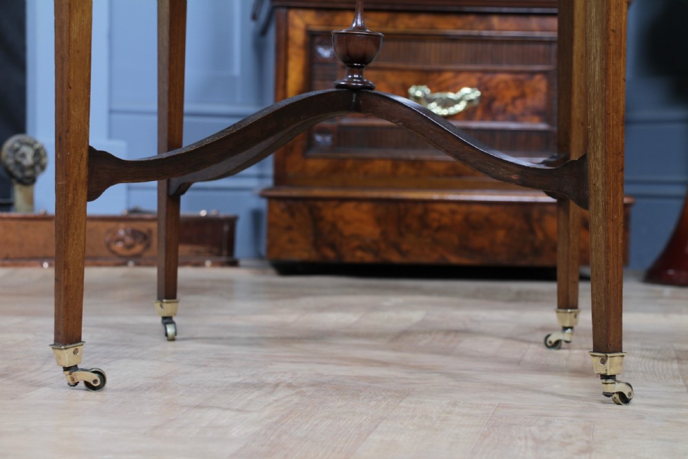 An Edwardian mahogany circular occasional table featuring a painted floral garland rim, central medallion, slender tapered legs, and an X-shaped cross-stretcher with a finial. View XII