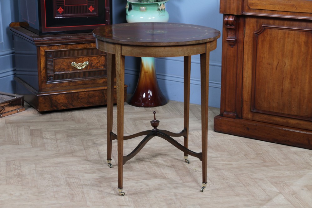 An Edwardian mahogany circular occasional table featuring a painted floral garland rim, central medallion, slender tapered legs, and an X-shaped cross-stretcher with a finial. View XIII