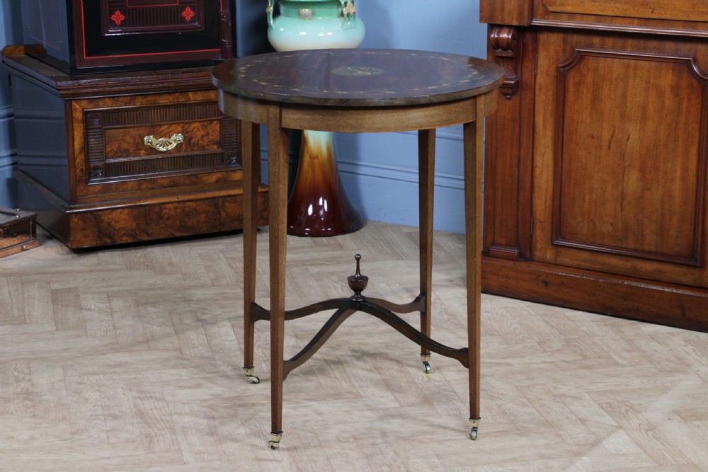 An Edwardian mahogany circular occasional table featuring a painted floral garland rim, central medallion, slender tapered legs, and an X-shaped cross-stretcher with a finial. View XIV