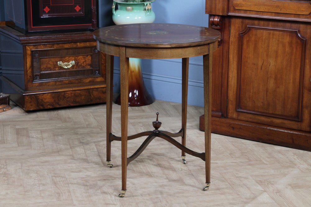 An Edwardian mahogany circular occasional table featuring a painted floral garland rim, central medallion, slender tapered legs, and an X-shaped cross-stretcher with a finial. View XV