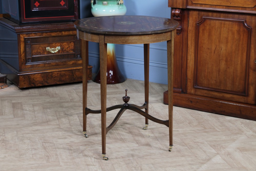 An Edwardian mahogany circular occasional table featuring a painted floral garland rim, central medallion, slender tapered legs, and an X-shaped cross-stretcher with a finial. View XVI
