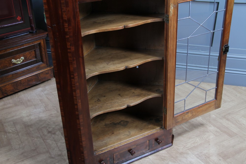 A Georgian mahogany wall-hanging corner cabinet featuring a single door with geometric glazed panels and a small base drawer. View III