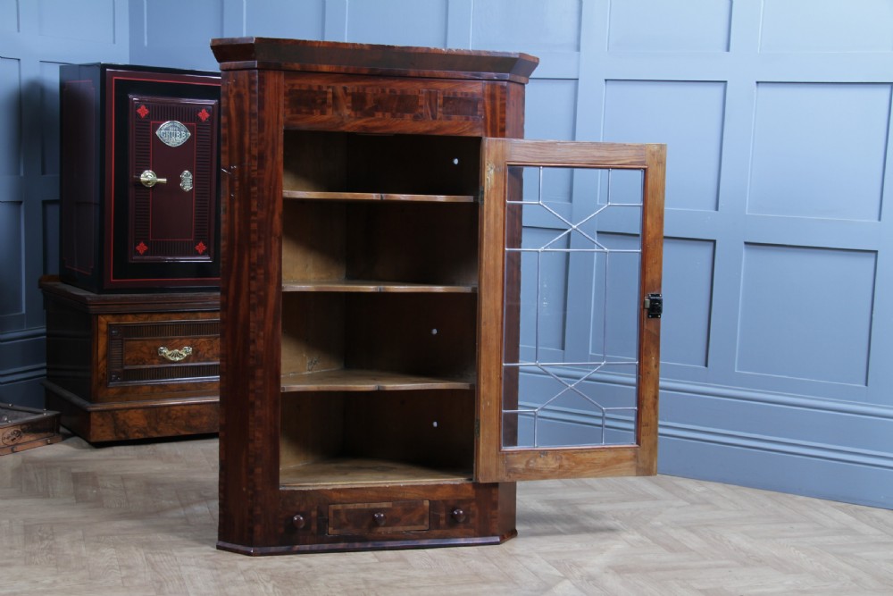 A Georgian mahogany wall-hanging corner cabinet featuring a single door with geometric glazed panels and a small base drawer. View IV