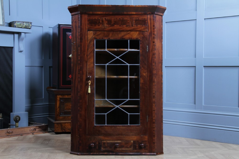 A Georgian mahogany wall-hanging corner cabinet featuring a single door with geometric glazed panels and a small base drawer. View VI