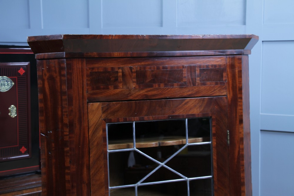 A Georgian mahogany wall-hanging corner cabinet featuring a single door with geometric glazed panels and a small base drawer. View VIII