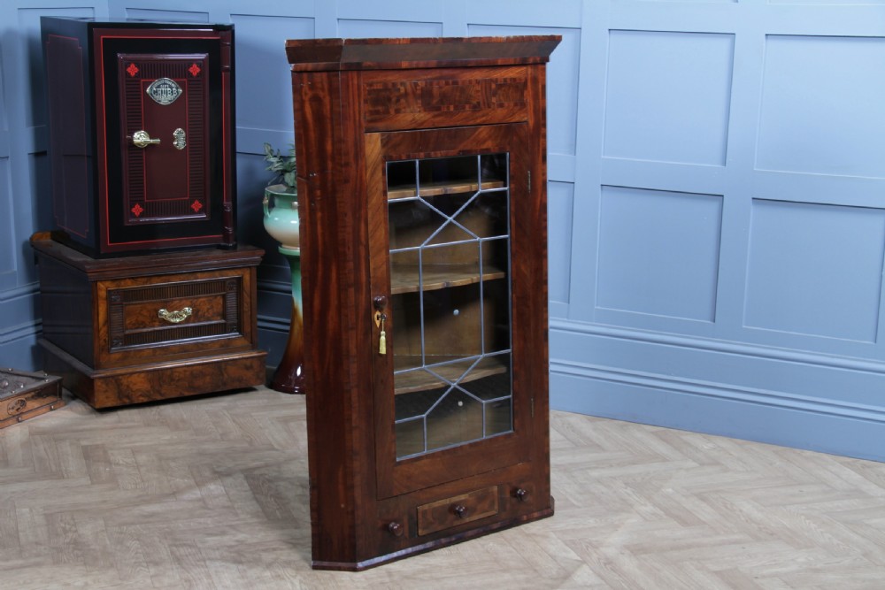 A Georgian mahogany wall-hanging corner cabinet featuring a single door with geometric glazed panels and a small base drawer. View XV