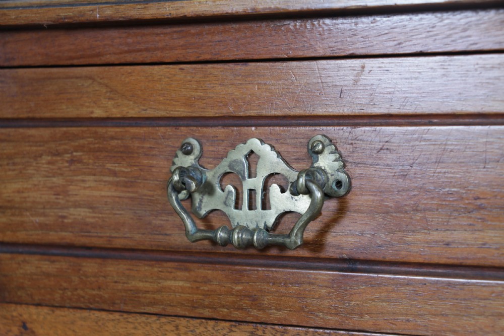 An Edwardian wall-mounted wooden cabinet featuring top finials, a carved floral panel, a central mirror, a lower drawer box with a brass handle, and bottom key hooks. View VII