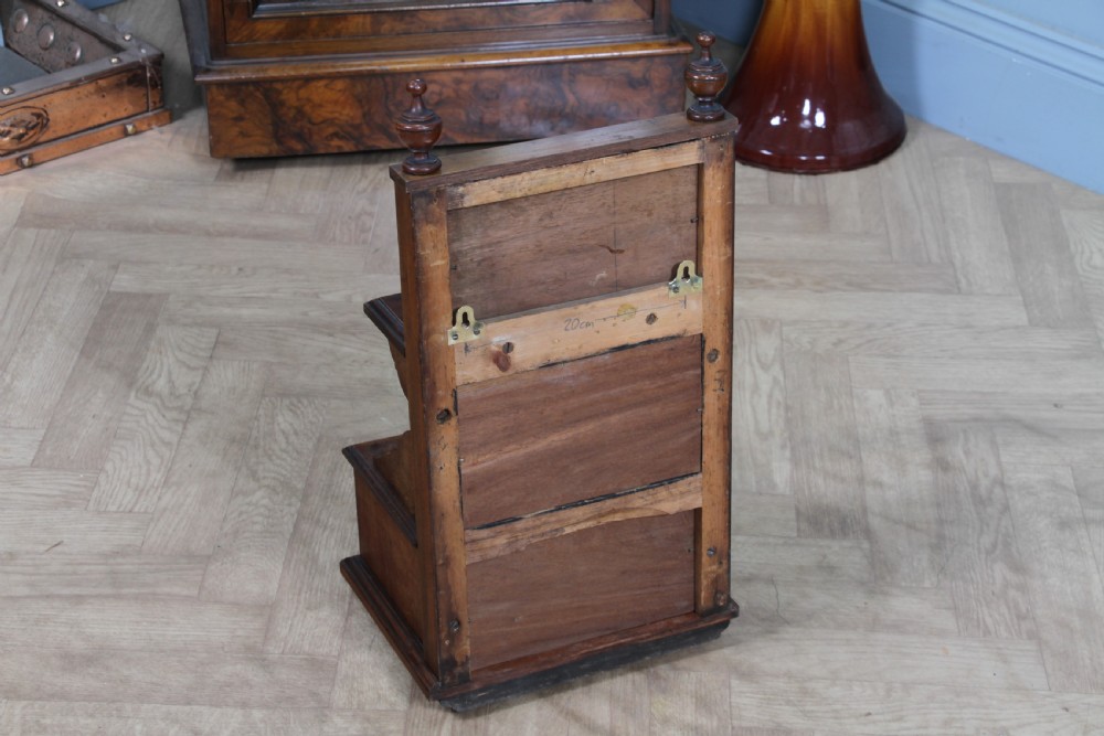 An Edwardian wall-mounted wooden cabinet featuring top finials, a carved floral panel, a central mirror, a lower drawer box with a brass handle, and bottom key hooks. View XXIV