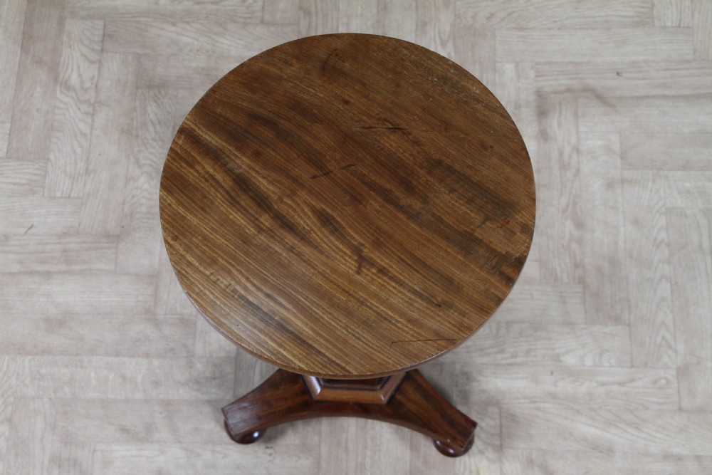 An antique William IV mahogany wine table featuring a circular top supported by a tapered faceted column and a triform base with bun feet. View II