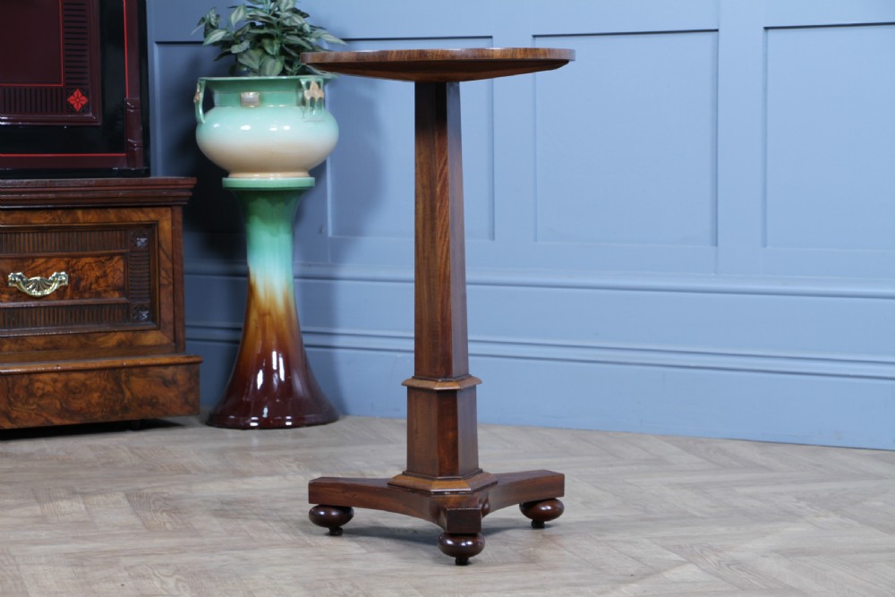 An antique William IV mahogany wine table featuring a circular top supported by a tapered faceted column and a triform base with bun feet. View III