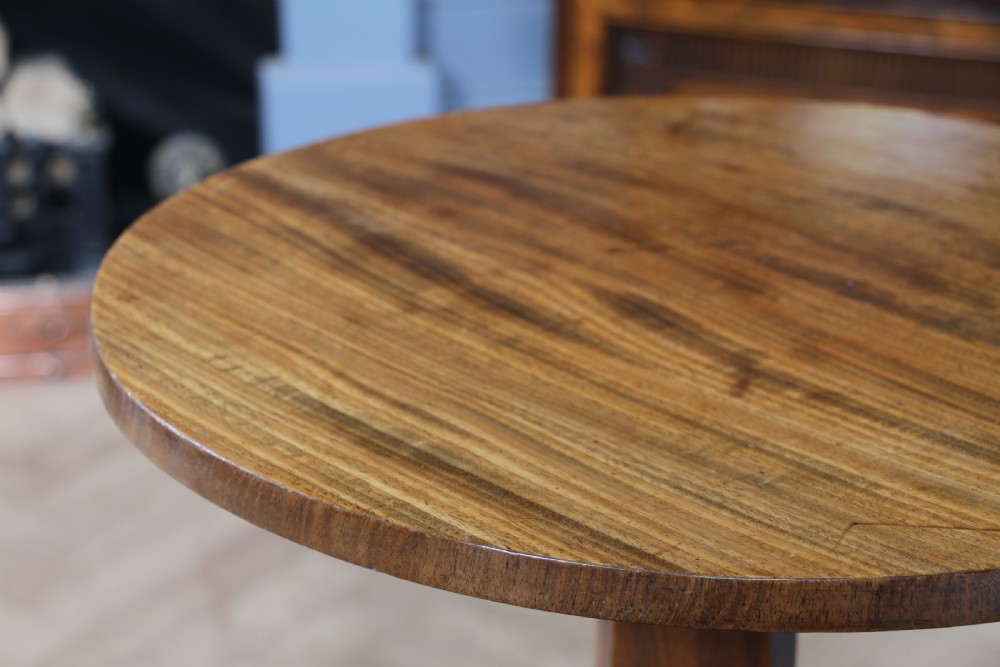 An antique William IV mahogany wine table featuring a circular top supported by a tapered faceted column and a triform base with bun feet. View V
