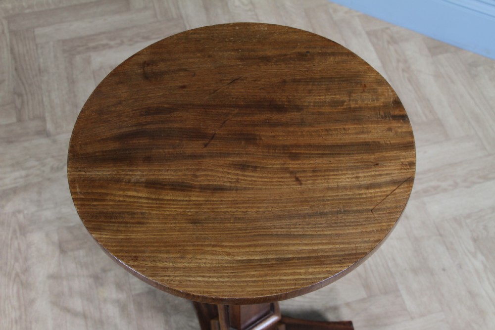 An antique William IV mahogany wine table featuring a circular top supported by a tapered faceted column and a triform base with bun feet. View VI
