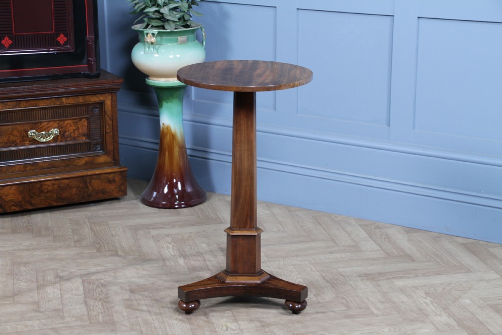 An antique William IV mahogany wine table featuring a circular top supported by a tapered faceted column and a triform base with bun feet. View VII