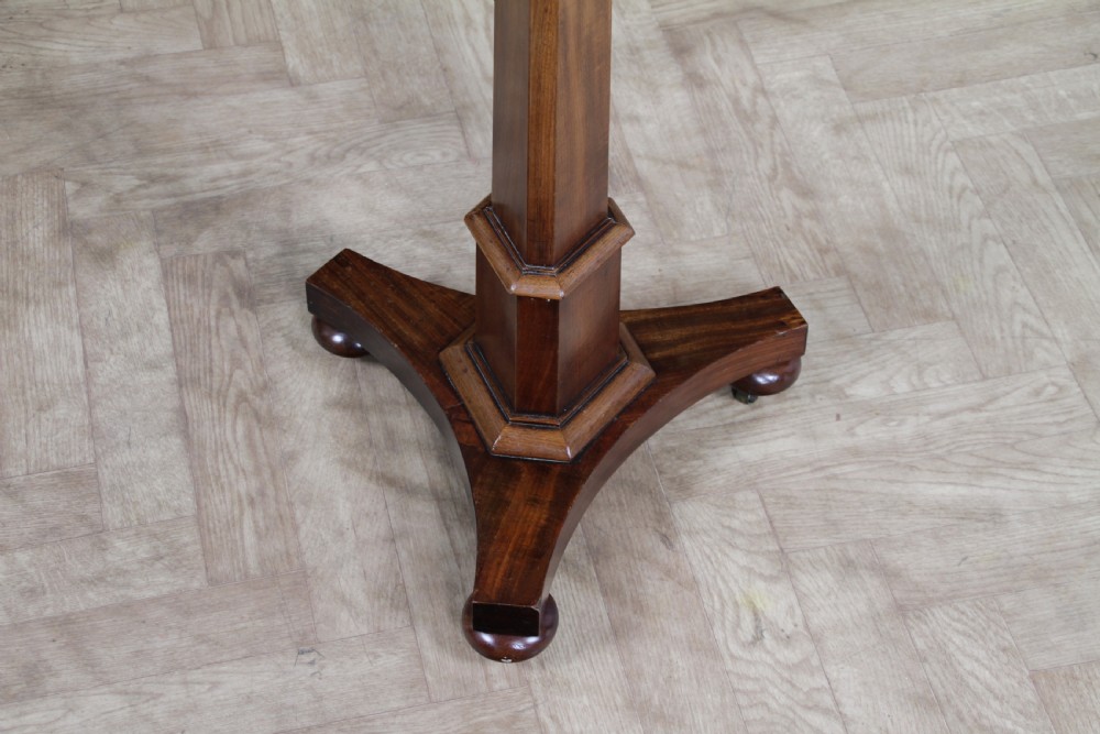An antique William IV mahogany wine table featuring a circular top supported by a tapered faceted column and a triform base with bun feet. View X