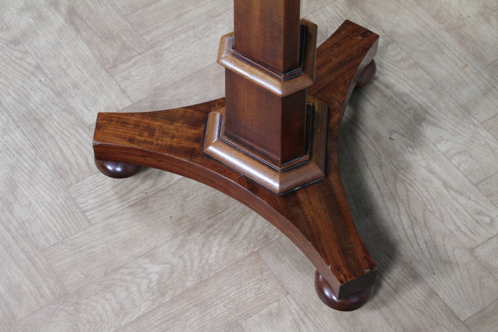 An antique William IV mahogany wine table featuring a circular top supported by a tapered faceted column and a triform base with bun feet. View XI