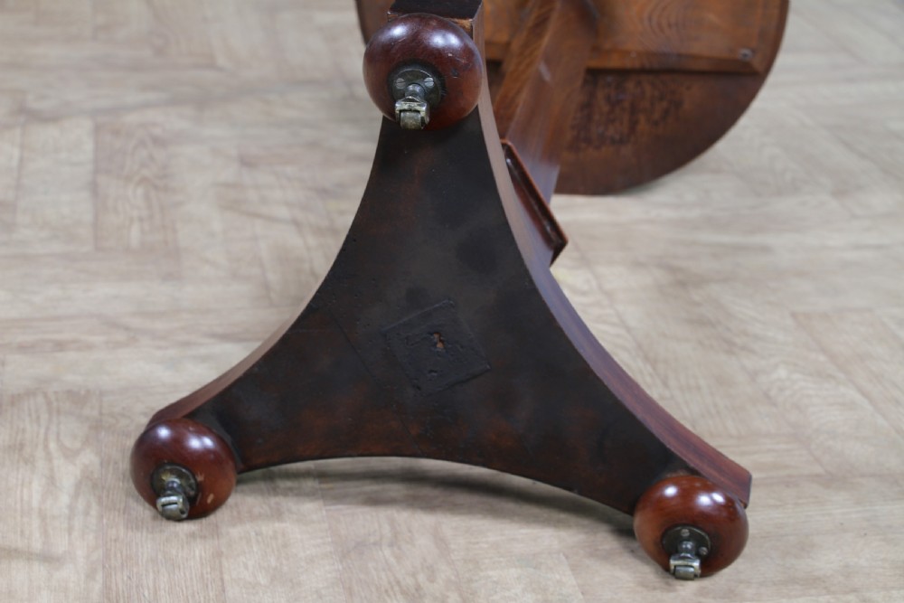 An antique William IV mahogany wine table featuring a circular top supported by a tapered faceted column and a triform base with bun feet. View XIV