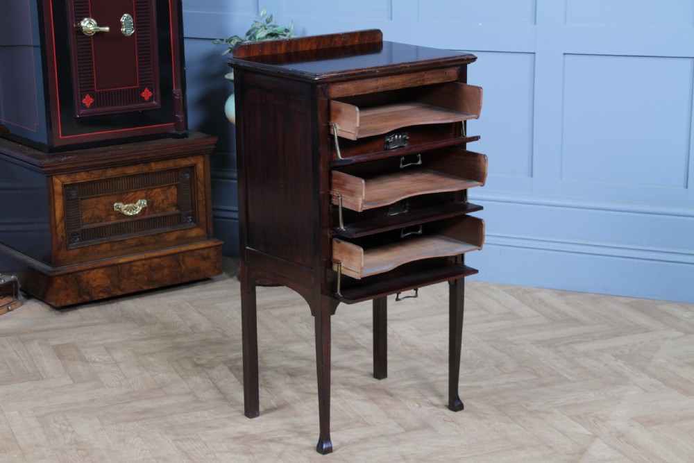 An Edwardian mahogany sheet music cabinet featuring five drop-front drawers fitted with Art Nouveau brass handles set on slender square legs. View VII