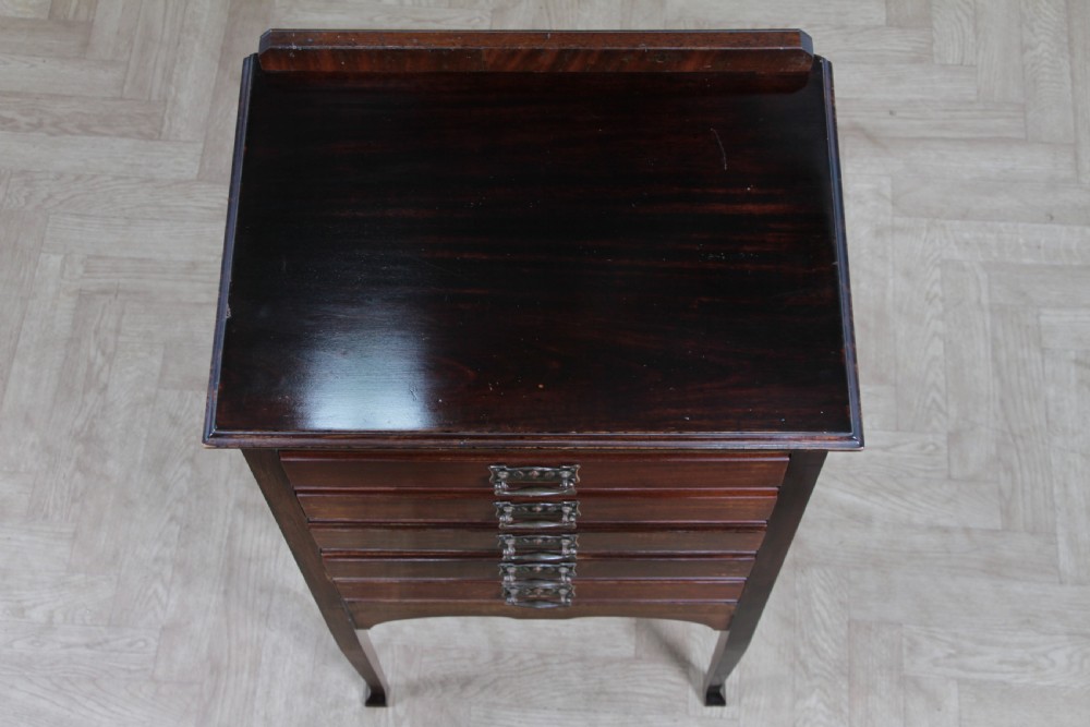 An Edwardian mahogany sheet music cabinet featuring five drop-front drawers fitted with Art Nouveau brass handles set on slender square legs. View IX