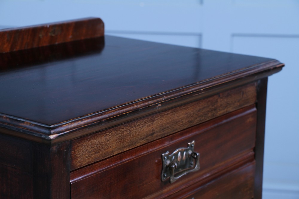 An Edwardian mahogany sheet music cabinet featuring five drop-front drawers fitted with Art Nouveau brass handles set on slender square legs. View X