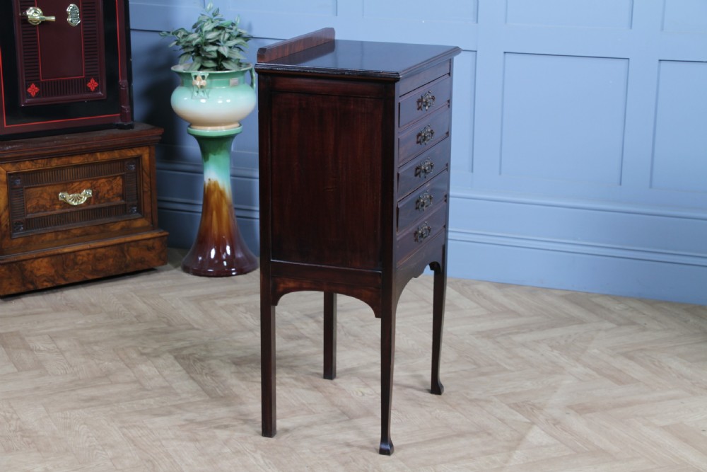 An Edwardian mahogany sheet music cabinet featuring five drop-front drawers fitted with Art Nouveau brass handles set on slender square legs. View XII