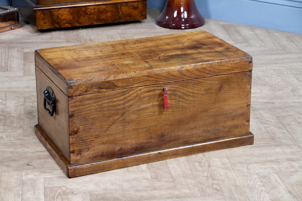 A rectangular solid elm tool chest featuring hand-cut dovetail joints, black iron side handles, and a warm wood grain finish.