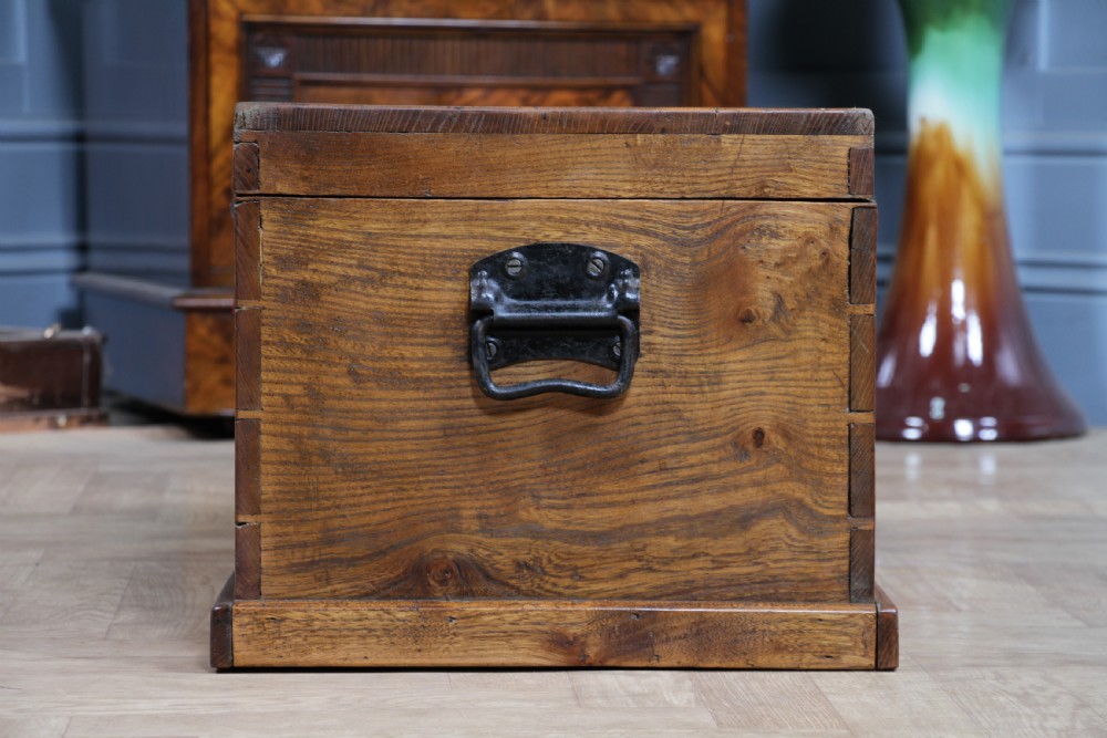 A rectangular solid elm tool chest featuring hand-cut dovetail joints, black iron side handles, and a warm wood grain finish. View X
