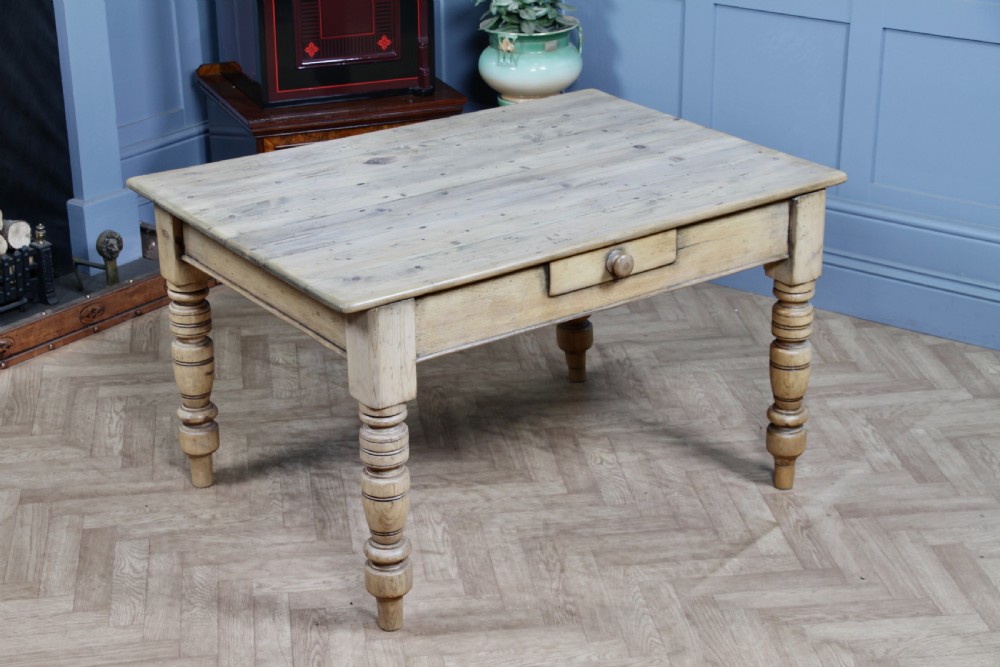 A restored Victorian pine kitchen table featuring a scrubbed rectangular plank top, a single frieze drawer with a wooden knob, and four turned legs.