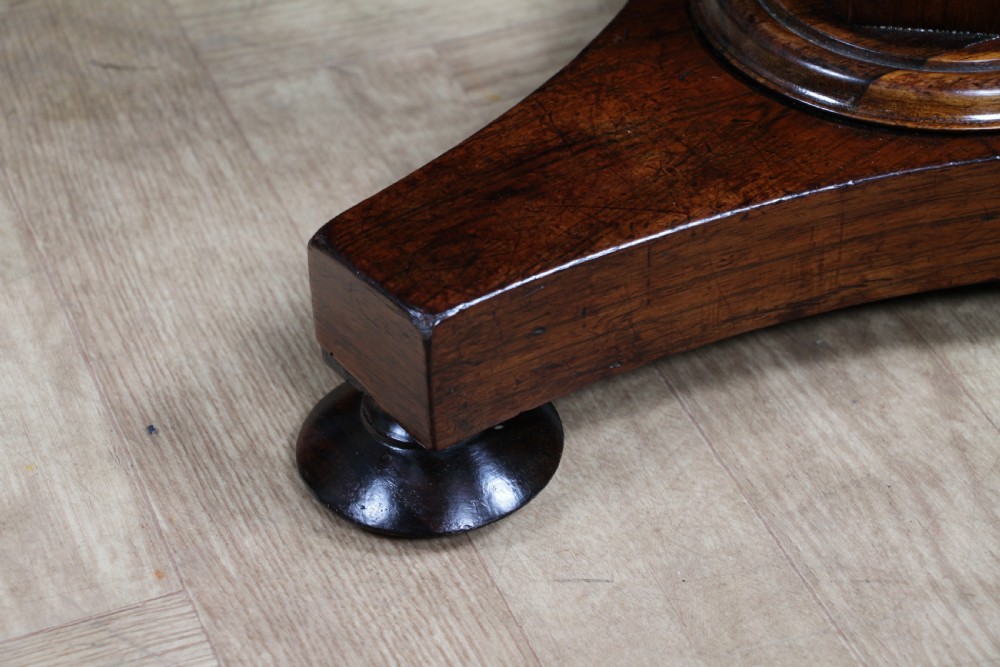 An early Victorian rosewood revolving piano stool featuring a circular floral needlepoint seat, a faceted central column, and a solid triform base with turned feet. View IX