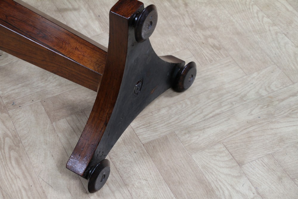 An early Victorian rosewood revolving piano stool featuring a circular floral needlepoint seat, a faceted central column, and a solid triform base with turned feet. View XVIII