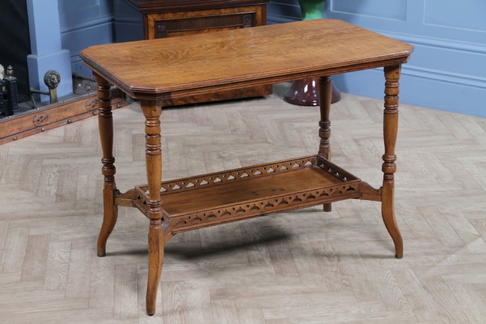 An Edwardian golden oak side table featuring a rectangular top, turned support legs, and a lower undertier shelf with a pierced cut-out gallery rail.