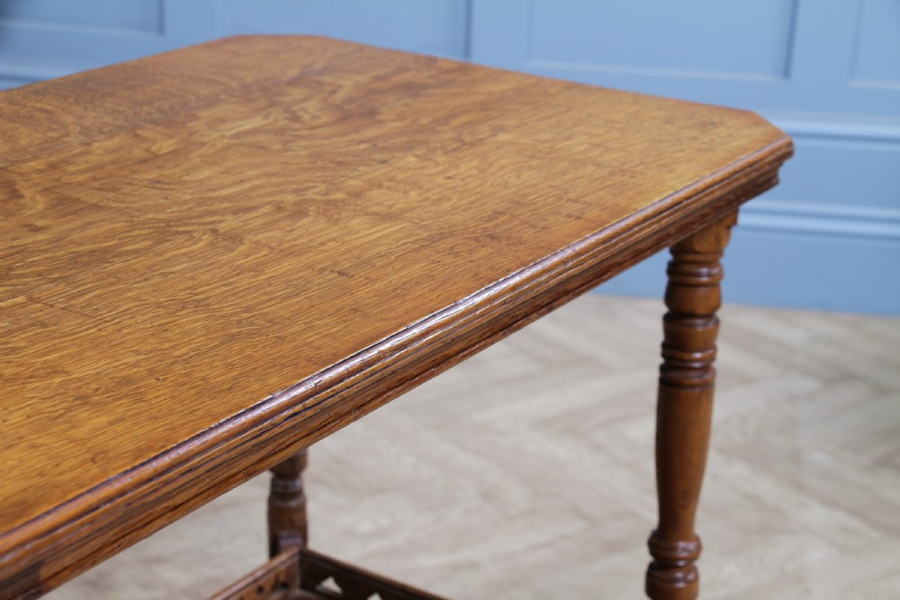 An Edwardian golden oak side table featuring a rectangular top, turned support legs, and a lower undertier shelf with a pierced cut-out gallery rail. View IV