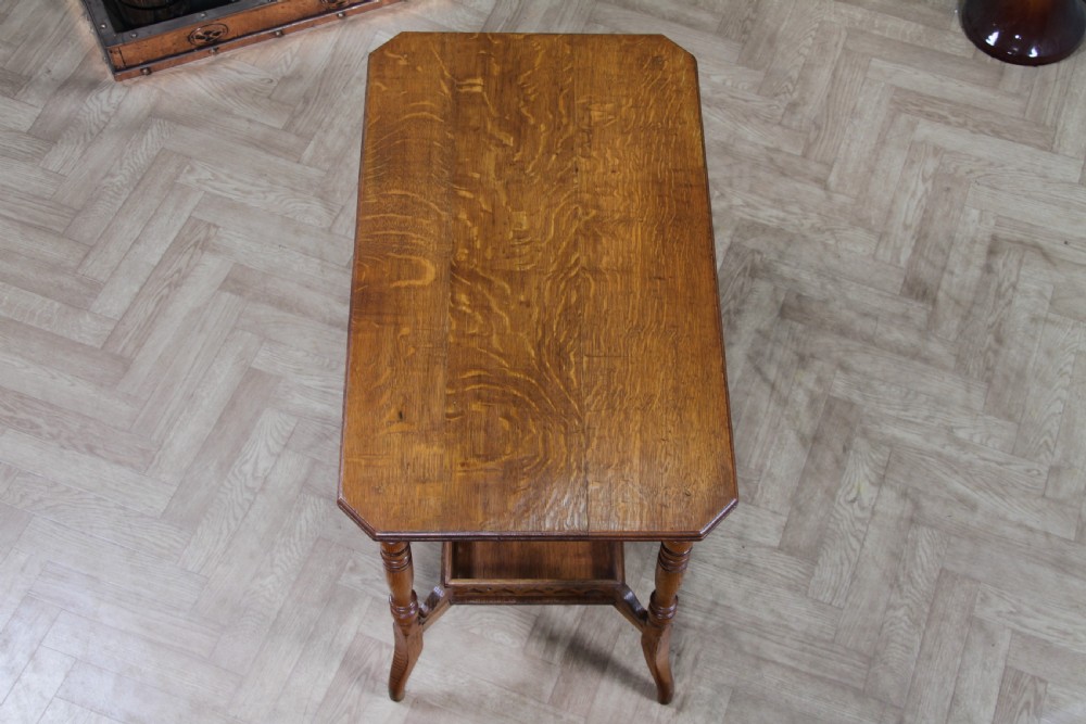 An Edwardian golden oak side table featuring a rectangular top, turned support legs, and a lower undertier shelf with a pierced cut-out gallery rail. View VI