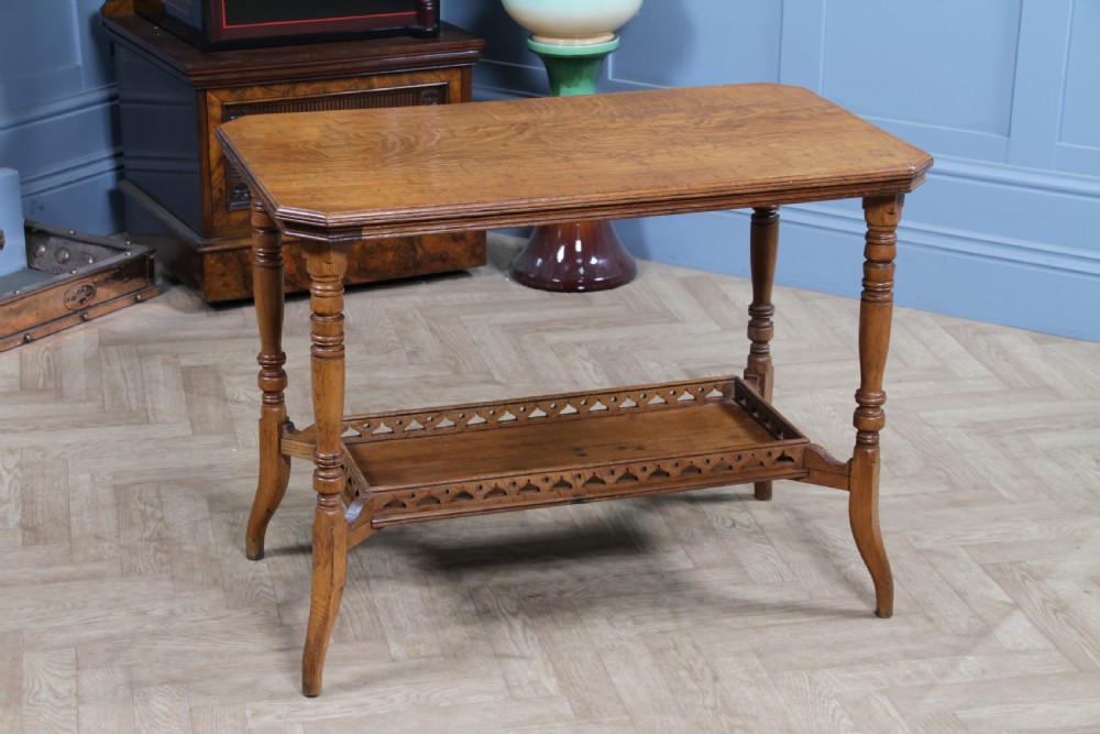 An Edwardian golden oak side table featuring a rectangular top, turned support legs, and a lower undertier shelf with a pierced cut-out gallery rail. View IX