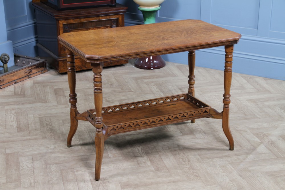 An Edwardian golden oak side table featuring a rectangular top, turned support legs, and a lower undertier shelf with a pierced cut-out gallery rail. View XI