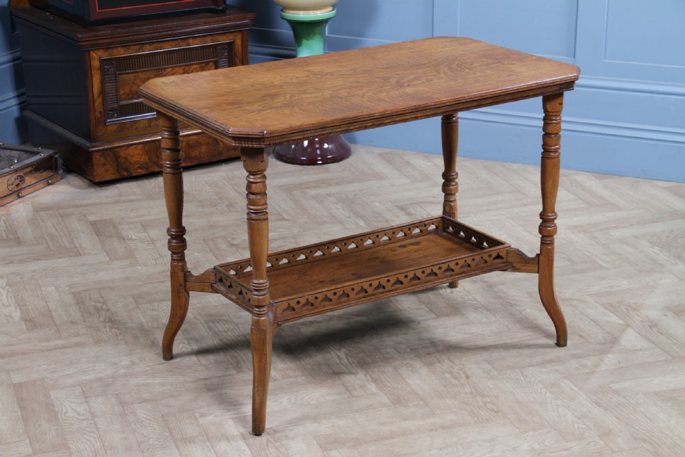 An Edwardian golden oak side table featuring a rectangular top, turned support legs, and a lower undertier shelf with a pierced cut-out gallery rail. View XII
