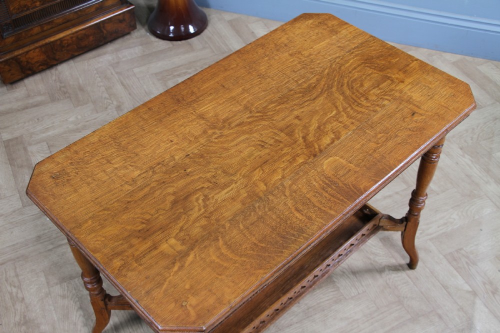 An Edwardian golden oak side table featuring a rectangular top, turned support legs, and a lower undertier shelf with a pierced cut-out gallery rail. View XVII