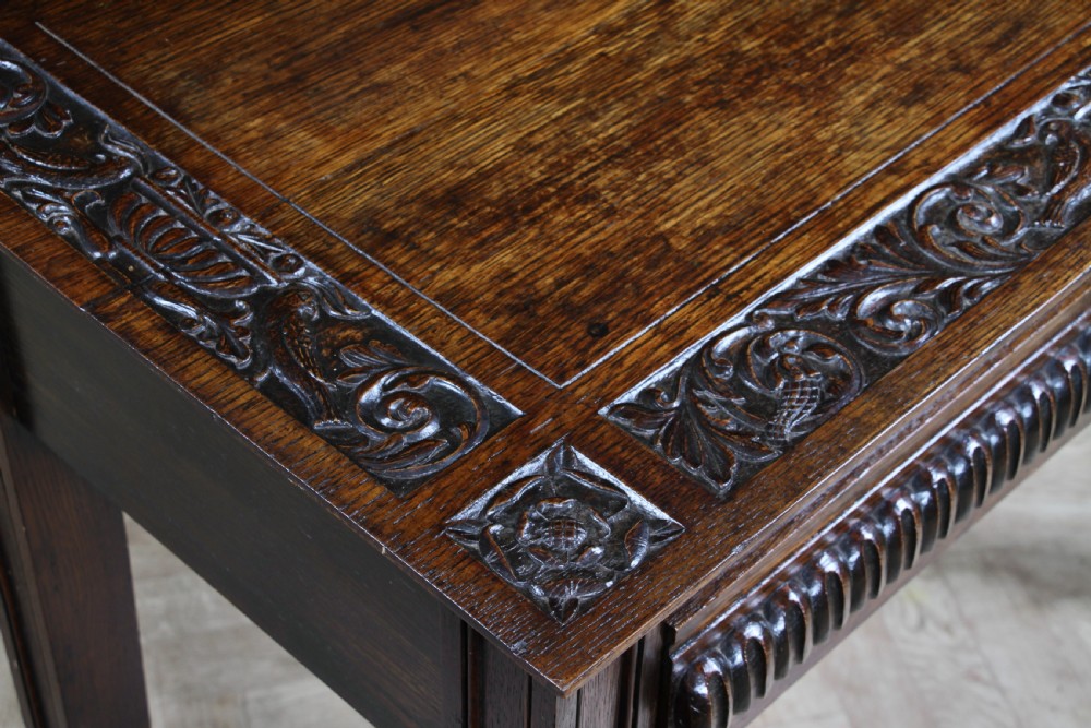 A dark carved oak side desk featuring a carved low gallery back, border-carved top surface, a single fluted drawer, and reeded legs. View XI