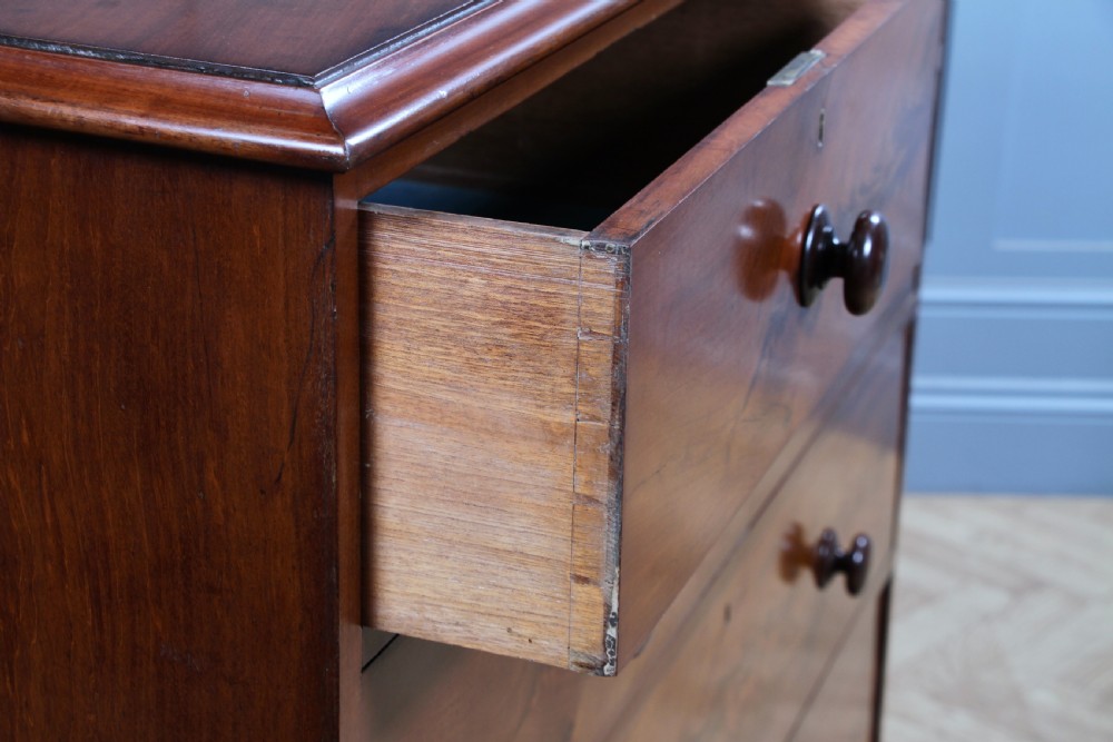 An antique Victorian flame mahogany chest of drawers featuring two short over three long drawers with turned wooden handles on a solid plinth base. View XI