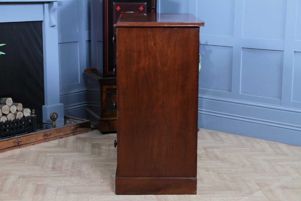 An antique Victorian flame mahogany chest of drawers featuring two short over three long drawers with turned wooden handles on a solid plinth base. View XIV