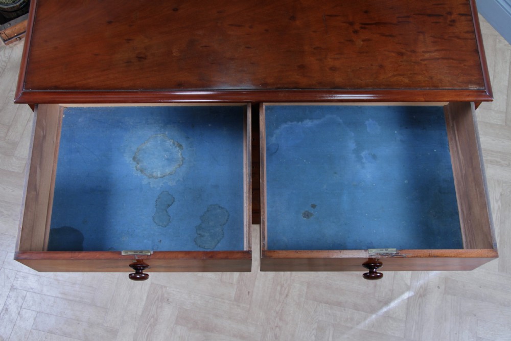 An antique Victorian flame mahogany chest of drawers featuring two short over three long drawers with turned wooden handles on a solid plinth base. View XVII