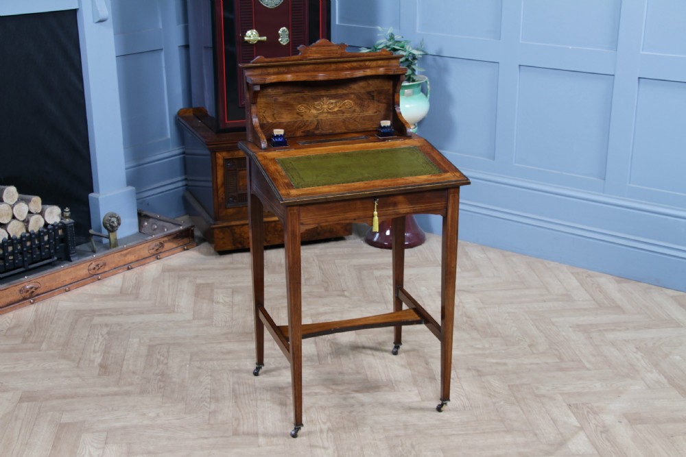A late Victorian inlaid rosewood bonheur du jour writing desk featuring a green leather surface, raised gallery shelf, and tapered legs with brass castors.