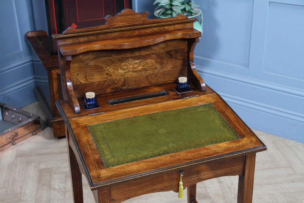 A late Victorian inlaid rosewood bonheur du jour writing desk featuring a green leather surface, raised gallery shelf, and tapered legs with brass castors. View II
