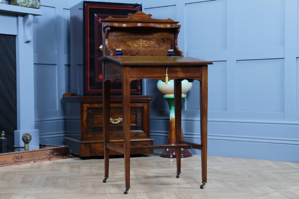 A late Victorian inlaid rosewood bonheur du jour writing desk featuring a green leather surface, raised gallery shelf, and tapered legs with brass castors. View IV