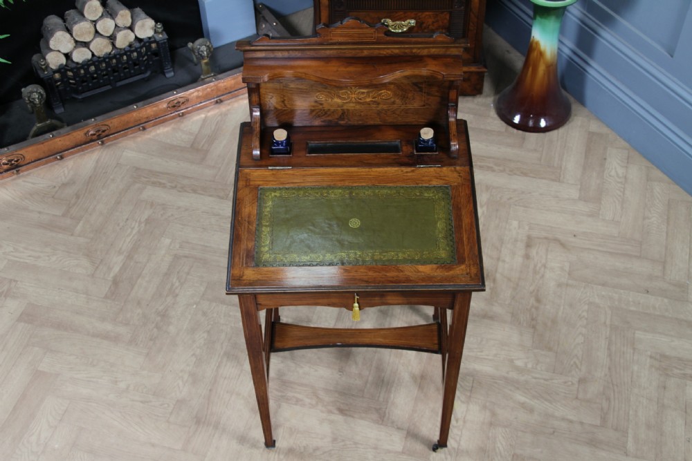 A late Victorian inlaid rosewood bonheur du jour writing desk featuring a green leather surface, raised gallery shelf, and tapered legs with brass castors. View VII