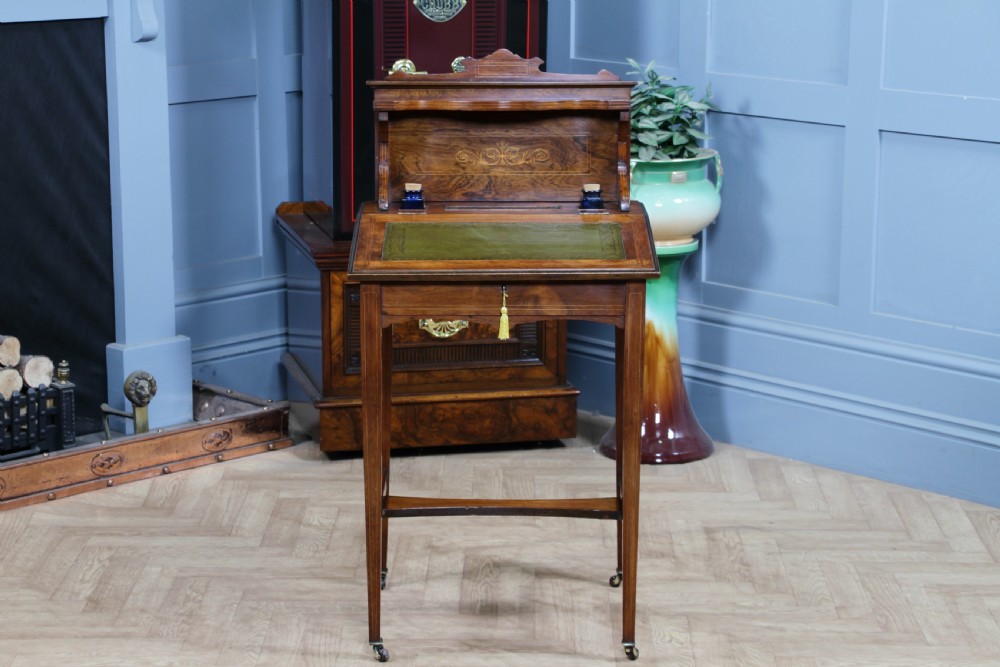 A late Victorian inlaid rosewood bonheur du jour writing desk featuring a green leather surface, raised gallery shelf, and tapered legs with brass castors. View VIII